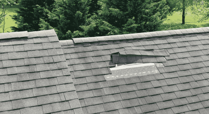 Close up of a damaged roof with lifted and missing tiles
